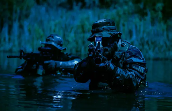 士兵们在沼泽地的中心移动 穿过沼泽的水域 热带丛林的夜晚 特遣部队隐蔽的夜间战术作战的极端条件 图库照片