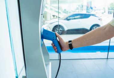 Man charge his electric car at city charging station.