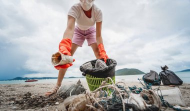 Kadın bir çevre bilimci plastikten ve diğer atıklardan sahil kenarını temizliyor..