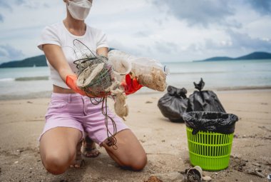 Kadın bir çevre bilimci plastikten ve diğer atıklardan sahil kenarını temizliyor..