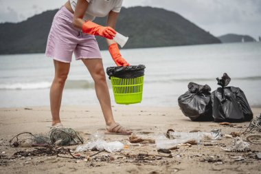 Kadın bir çevre bilimci plastikten ve diğer atıklardan sahil kenarını temizliyor..