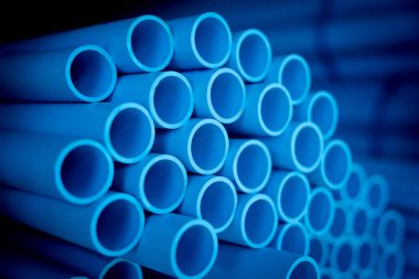 Üst üste dizilmiş mavi plastik boruların arkaplanı.