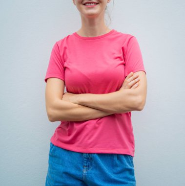Gri bir duvarın arka planında pembe, boş tişört giyen kadın model.