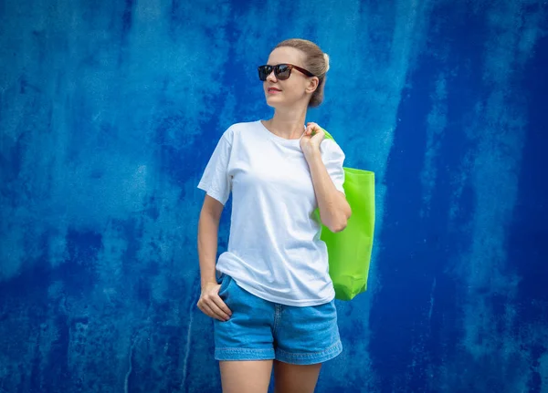 青い壁を背景に白いTシャツを着た女性モデル — ストック写真