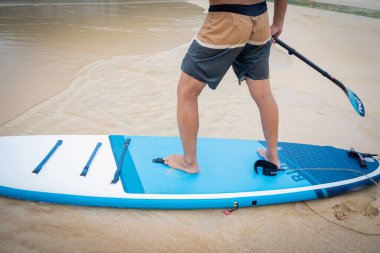 Sakin günbatımı denizinde sörf tahtası olan genç bir adam..