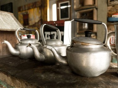 Alüminyum çaydanlıklar ve karanlık bir arka planda soba..