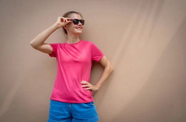 砂浜を背景にピンクのTシャツを着た女性モデル — ストック写真