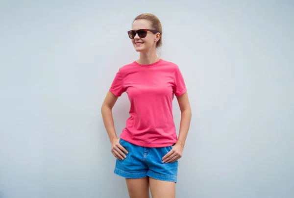 グレーの壁を背景にピンクのTシャツを着た女性モデル — ストック写真