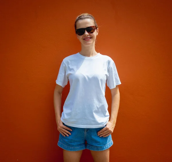 オレンジの壁を背景に白いTシャツを着た女性モデル — ストック写真