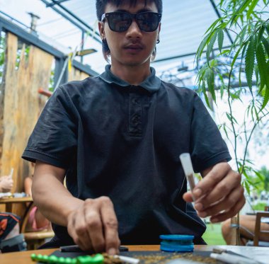 Genç adam tıbbi marihuanayla sigara yapıyor..