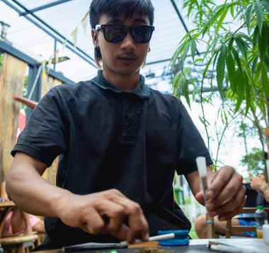 Genç adam tıbbi marihuanayla sigara yapıyor..