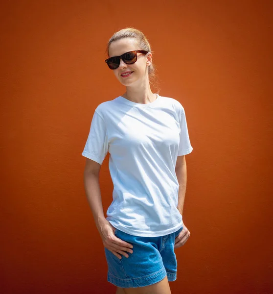 オレンジの壁を背景に白いTシャツを着た女性モデル — ストック写真