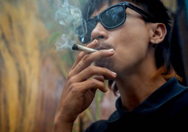Genç adam tıbbi marihuanayla sigara içiyor..