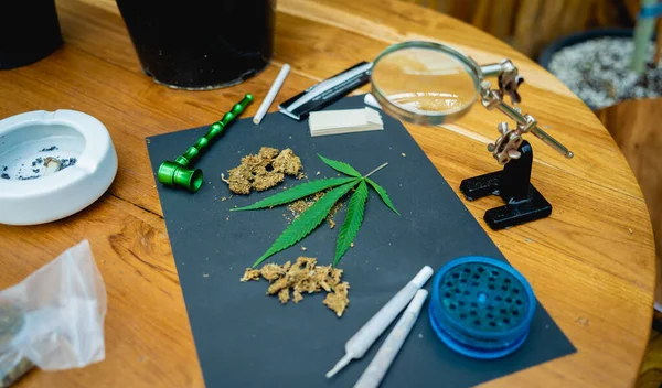 木製のテーブルの上に大麻やタバコの関節や芽 — ストック写真