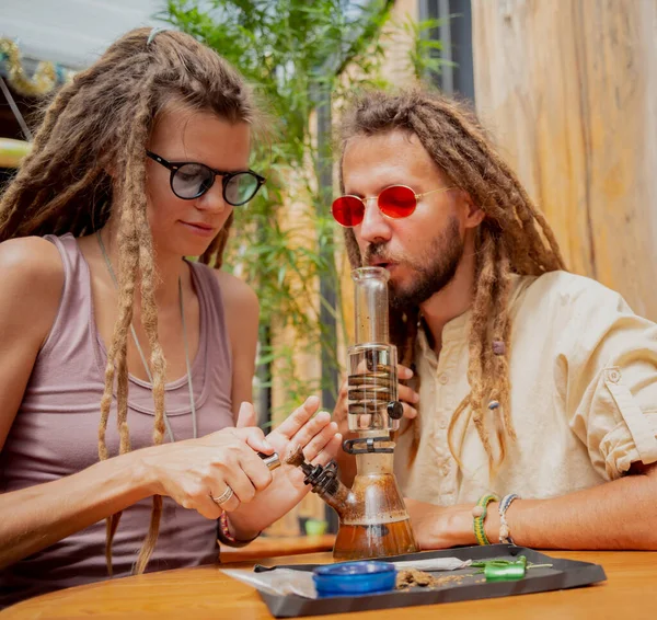 Hippie Style Couple Smoking Medical Marijuana Using Bong — Stockfoto