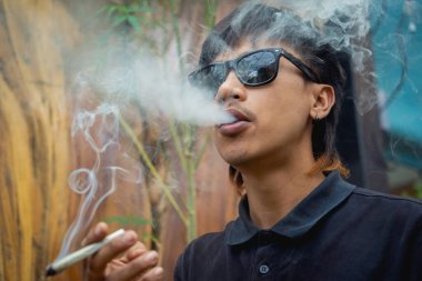 Genç adam tıbbi marihuanayla sigara içiyor..