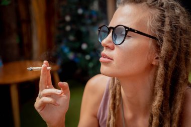 Hippi tarzı kadın tıbbi marihuanayla sigara içiyor..