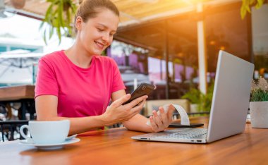 Woman using contactless payment by mobile phone with QR code at cafe.