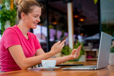 Cafe 'de QR kodlu cep telefonuyla ulaşılamaz ödeme yapan bir kadın..