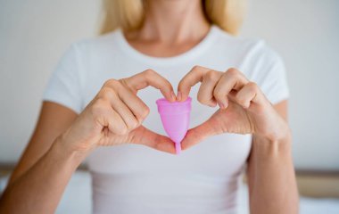 Young beautiful woman at home holding a menstrual cup in her hands.