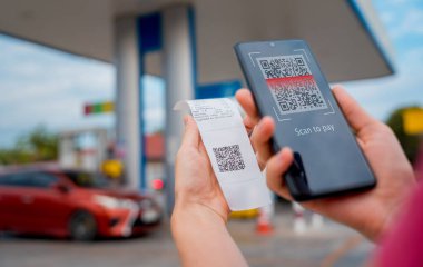 Araç dolum istasyonunda QR kodlu cep telefonuyla ücretsiz ödeme yapan bir kadın..