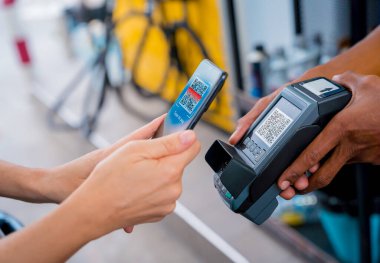 Araç dolum istasyonunda QR kodlu cep telefonuyla ücretsiz ödeme yapan bir kadın..
