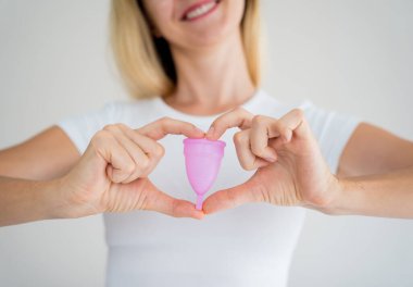 Young beautiful woman at home holding a menstrual cup in her hands.