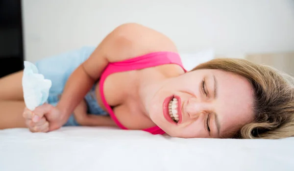 beautiful woman feels pain during menstruation on the bed.