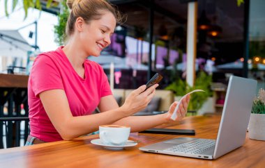 Cafe 'de QR kodlu cep telefonuyla ulaşılamaz ödeme yapan bir kadın..