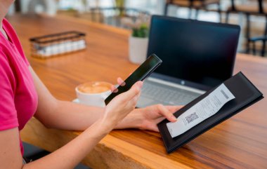 Cafe 'de QR kodlu cep telefonuyla ulaşılamaz ödeme yapan bir kadın..
