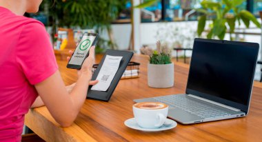 Cafe 'de QR kodlu cep telefonuyla ulaşılamaz ödeme yapan bir kadın..