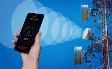 5G baz istasyonunun arka planında telefon olan eller sinyal alıyor..