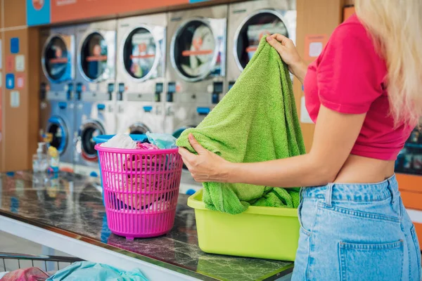 年轻漂亮的女人在洗衣店洗衣服和擦干衣服 — 图库照片