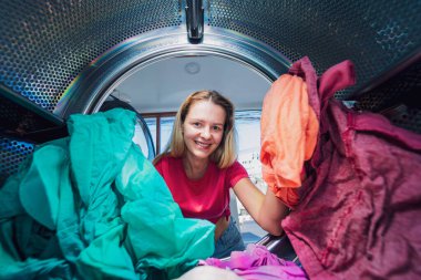 Genç ve güzel bir kadın çamaşırhanede çamaşır yıkar ve kurutur..