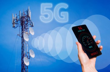5G baz istasyonunun arka planında telefon olan eller sinyal alıyor..