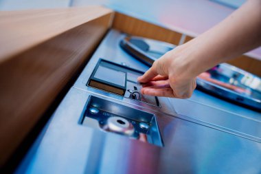 Çamaşırhanedeki çamaşır makinesine para koyan genç bir kadın..