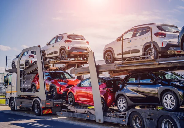 Stock image Car carrier trailer transports cars on highway at blue sky background