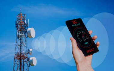 5G baz istasyonunun arka planında telefon olan eller sinyal alıyor..