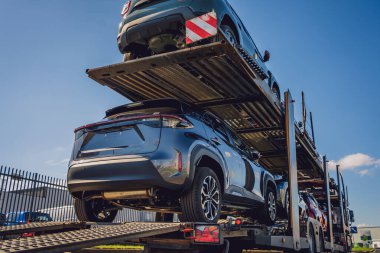 Taşıyıcı karavan mavi gökyüzü arka planında otoyolda araba taşıyor.