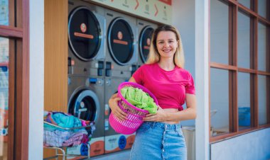 Genç ve güzel bir kadın çamaşırhanede çamaşır yıkar ve kurutur..