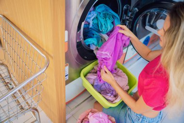 Genç ve güzel bir kadın çamaşırhanede çamaşır yıkar ve kurutur..