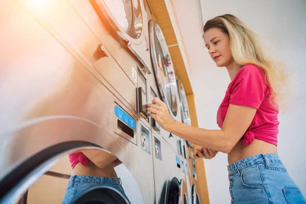 年轻漂亮的女人在洗衣店洗衣服和擦干衣服 — 图库照片