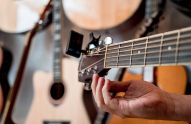 Genç bir müzisyen gitar dükkanında klasik gitar akort ediyor..