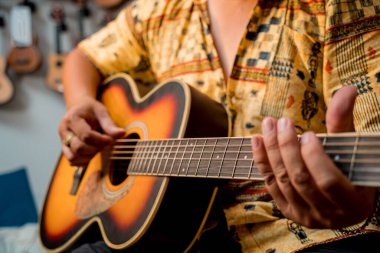 Genç bir müzisyen gitar dükkanında klasik gitar akort ediyor..