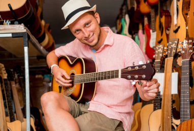 Genç bir müzisyen gitar dükkanında klasik gitar akort ediyor..