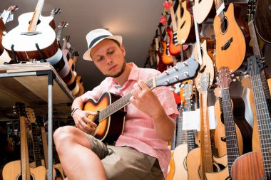 Genç bir müzisyen gitar dükkanında klasik gitar akort ediyor..