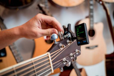 Genç bir müzisyen gitar dükkanında klasik gitar akort ediyor..