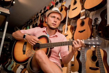 Genç bir müzisyen gitarı gitar dükkanında test ediyor..