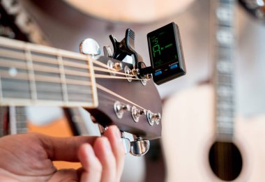 Genç bir müzisyen gitar dükkanında klasik gitar akort ediyor..