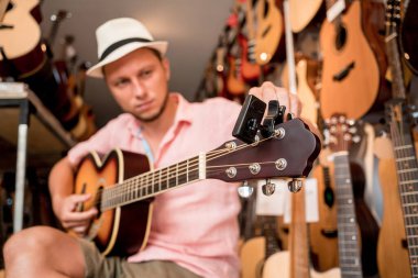 Genç bir müzisyen gitar dükkanında klasik gitar akort ediyor..